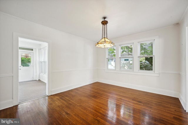 spare room featuring crown molding, baseboards, and dark wood-type flooring