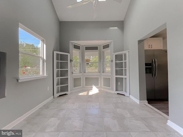 interior space with baseboards, a ceiling fan, and high vaulted ceiling