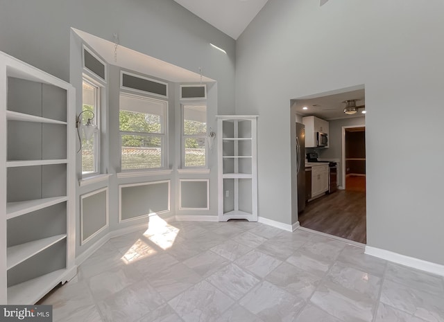 interior space with high vaulted ceiling, baseboards, and marble finish floor
