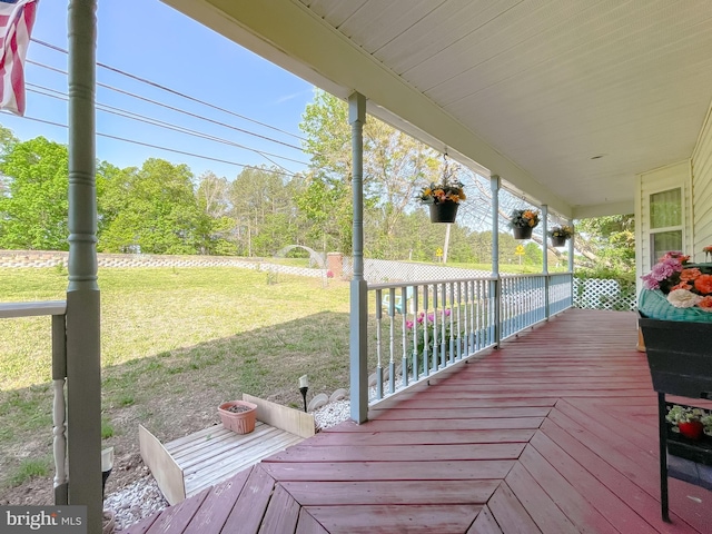 wooden terrace with a lawn and covered porch