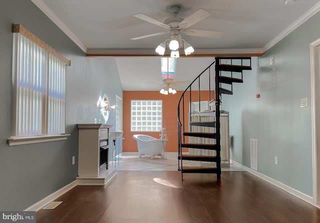 stairway featuring visible vents, ornamental molding, baseboards, a fireplace with raised hearth, and a ceiling fan