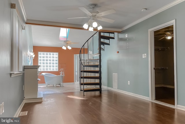 staircase featuring visible vents, crown molding, wood finished floors, ceiling fan, and a skylight
