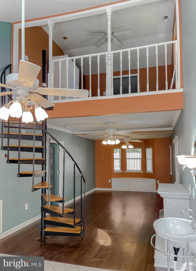 stairs featuring ceiling fan, visible vents, wood finished floors, and a high ceiling