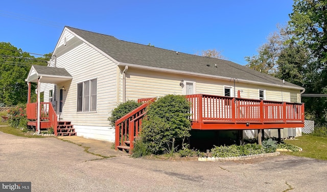 rear view of house featuring a wooden deck and a shingled roof