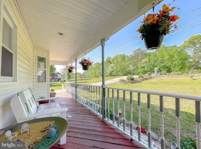 wooden deck featuring a lawn and a porch