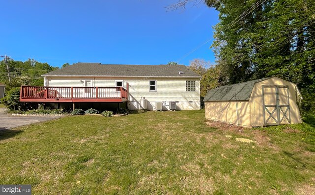 back of house with a lawn, a deck, an outbuilding, central air condition unit, and a shed