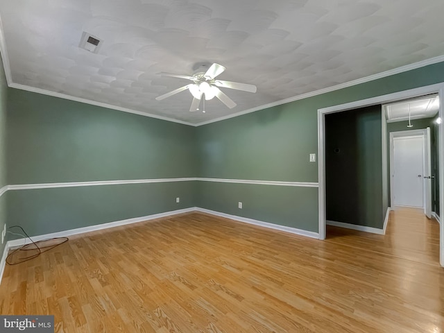 empty room with ceiling fan, light wood-style flooring, attic access, baseboards, and visible vents