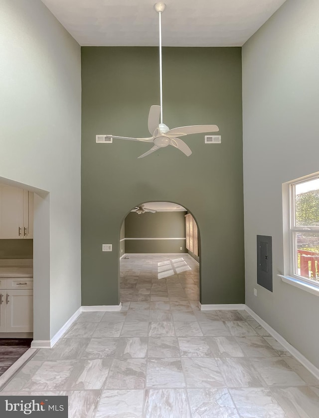 interior space with a ceiling fan, a high ceiling, and visible vents