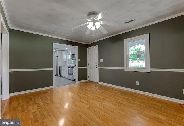 spare room featuring visible vents, crown molding, baseboards, a ceiling fan, and light wood-style flooring
