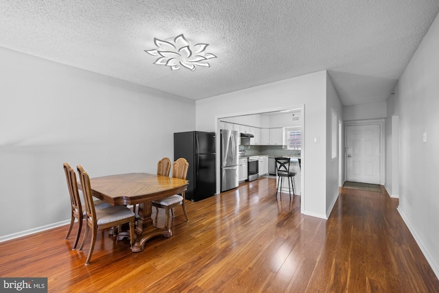 dining area with a textured ceiling, dark wood-style floors, and baseboards