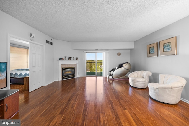 living area featuring a textured ceiling, wood finished floors, and visible vents