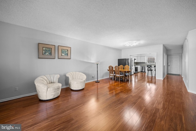living area featuring baseboards, a textured ceiling, and wood finished floors