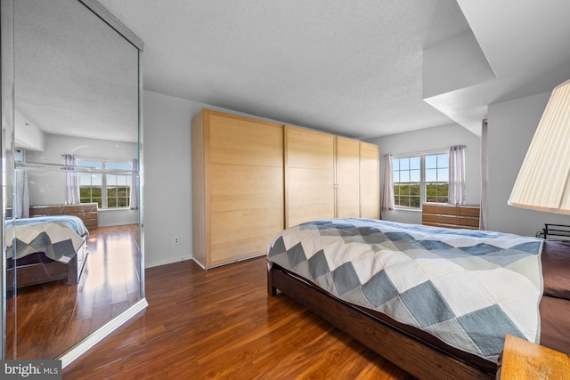 bedroom with baseboards, a textured ceiling, and wood finished floors