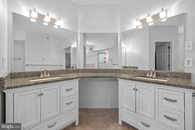 bathroom with a sink, walk in shower, and two vanities