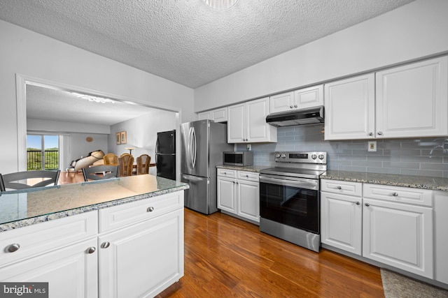 kitchen with white cabinets, dark wood-style flooring, a textured ceiling, stainless steel appliances, and under cabinet range hood