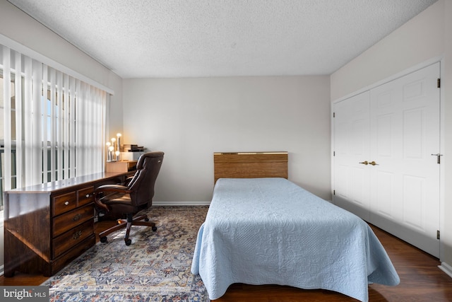 bedroom with baseboards, a textured ceiling, and wood finished floors