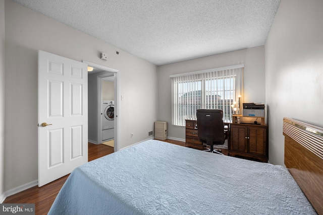 bedroom featuring baseboards, a textured ceiling, dark wood-style flooring, and washer / clothes dryer