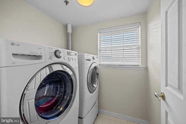 washroom featuring laundry area, baseboards, and washing machine and clothes dryer
