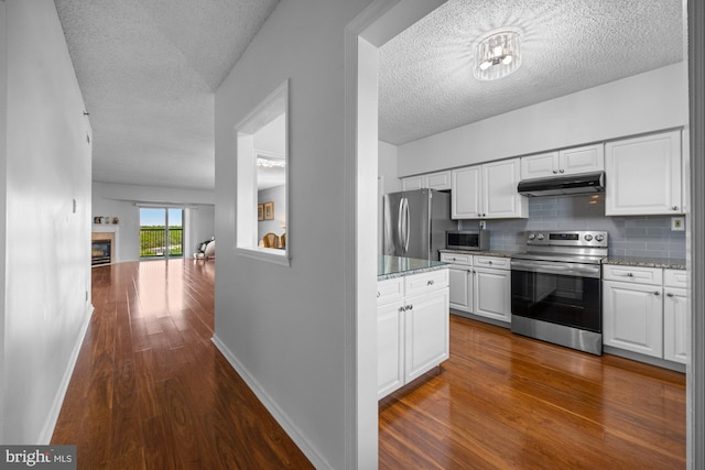 kitchen with a textured ceiling, stainless steel appliances, white cabinetry, dark wood-type flooring, and under cabinet range hood