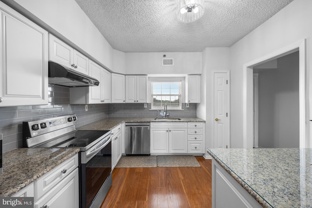 kitchen featuring a textured ceiling, visible vents, a sink, under cabinet range hood, and stainless steel appliances