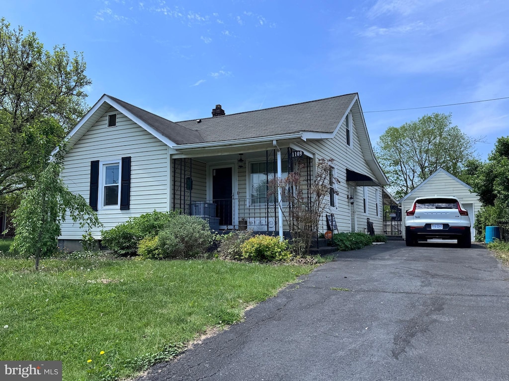 view of front of house with a garage, covered porch, a front yard, roof with shingles, and a chimney
