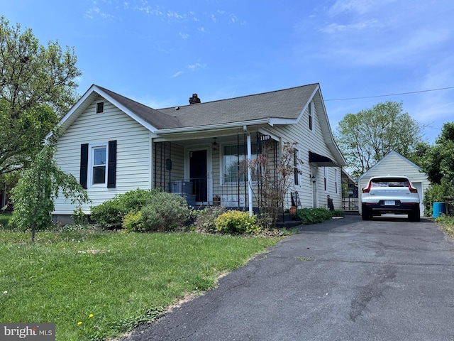 view of front of house with a garage, covered porch, a front yard, roof with shingles, and a chimney