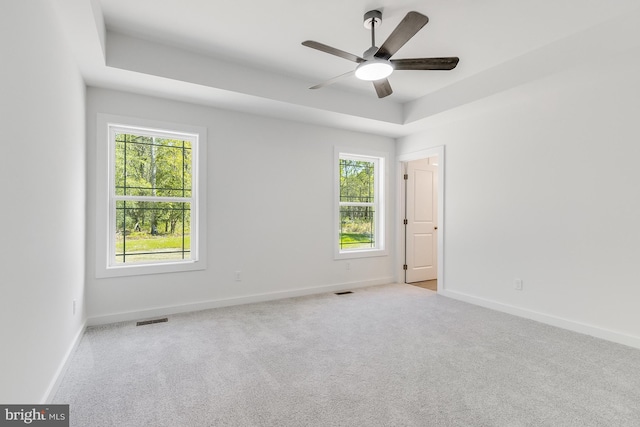 empty room with carpet floors, a ceiling fan, baseboards, and visible vents