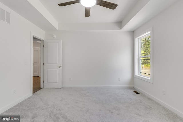 spare room with visible vents, carpet, ceiling fan, and a tray ceiling
