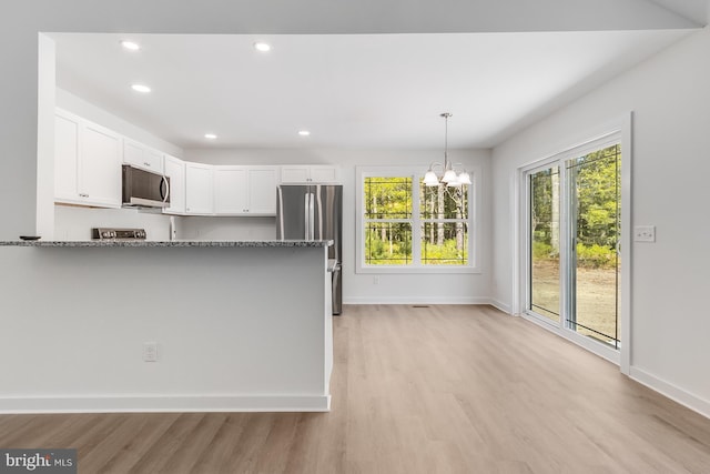 kitchen featuring appliances with stainless steel finishes, light stone counters, a chandelier, light wood-style flooring, and white cabinetry