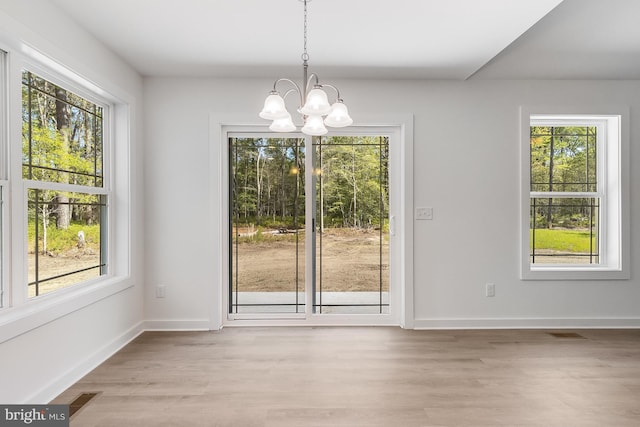 unfurnished dining area featuring light wood-style floors, baseboards, a notable chandelier, and visible vents