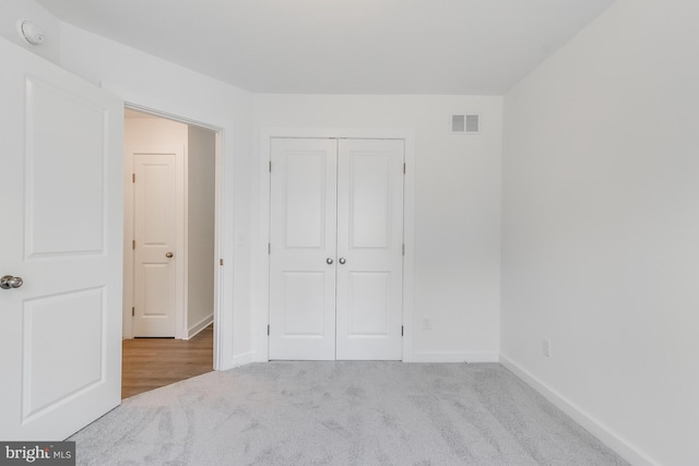 unfurnished bedroom featuring carpet floors, baseboards, visible vents, and a closet