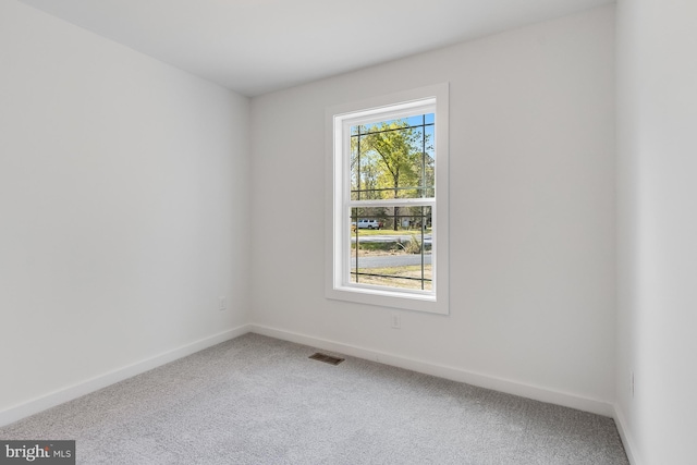 carpeted spare room featuring baseboards and visible vents