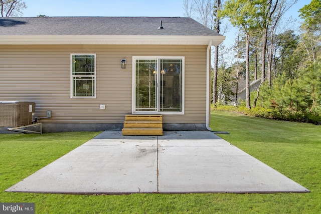 rear view of house featuring a shingled roof, central AC, entry steps, a patio area, and a lawn