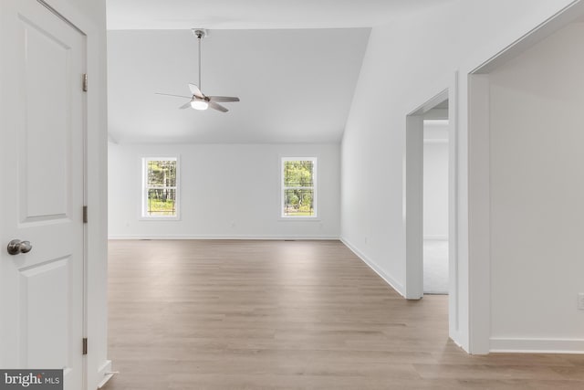 empty room with light wood-type flooring, a ceiling fan, lofted ceiling, and a wealth of natural light