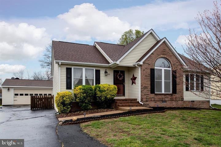 ranch-style house with brick siding, a shingled roof, a front yard, and a detached garage