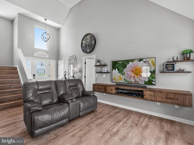 living area featuring stairs, high vaulted ceiling, an inviting chandelier, and wood finished floors