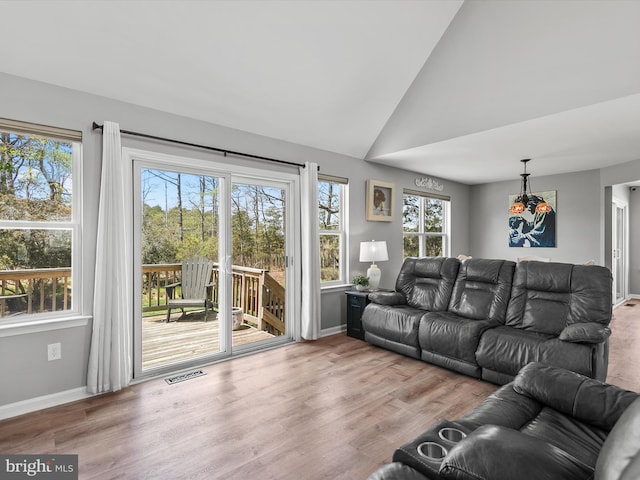 living area with baseboards, visible vents, vaulted ceiling, and a wealth of natural light