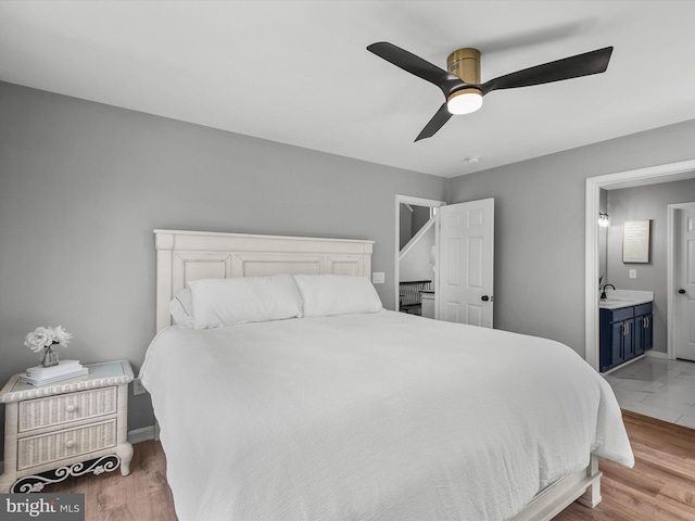 bedroom featuring a sink, baseboards, a ceiling fan, and connected bathroom