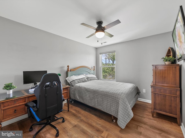 bedroom featuring visible vents, a ceiling fan, baseboards, and wood finished floors