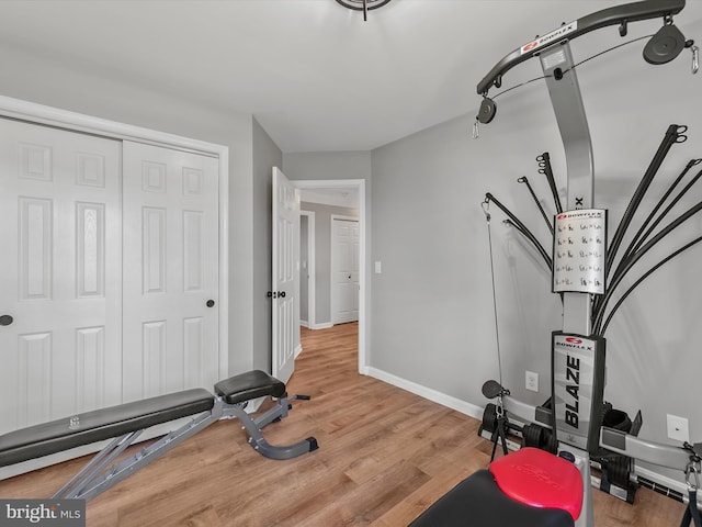 exercise room with baseboards and wood finished floors
