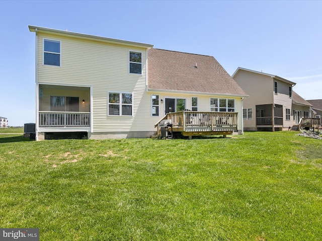 back of property with a yard, a wooden deck, a shingled roof, and central air condition unit