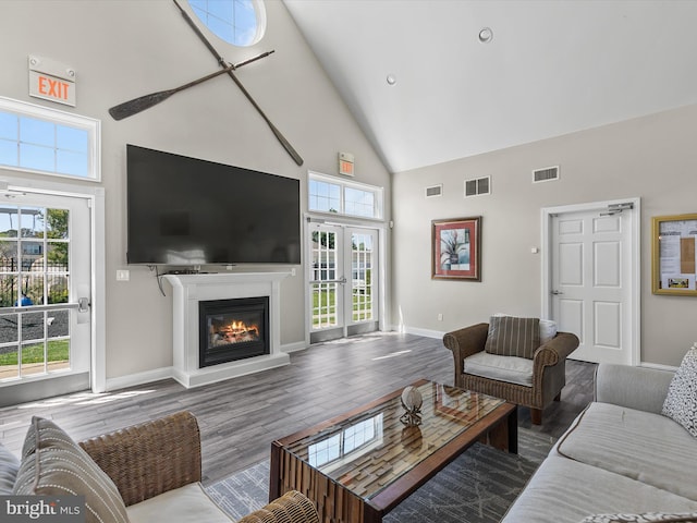 living area with visible vents, plenty of natural light, and high vaulted ceiling