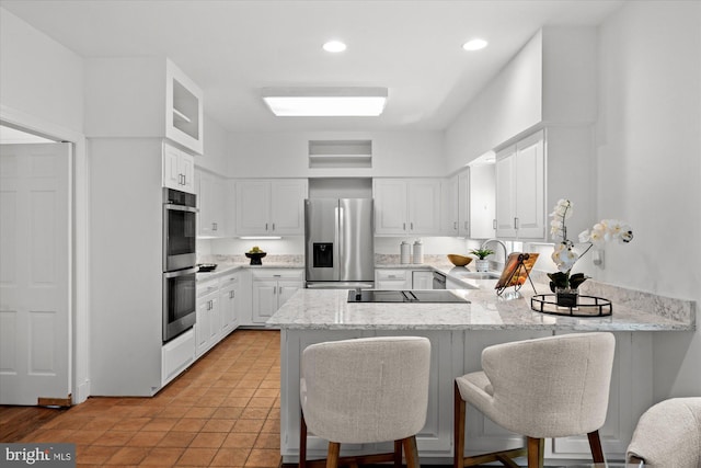 3233 Ellicott St NW, Washington, DC 20008 - kitchen featuring a sink, a peninsula, white cabinets, light stone countertops, and appliances with stainless steel finishes