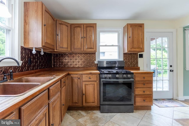 1724 E Branch Rd, State College, PA 16801 - kitchen with stainless steel range with gas stovetop, a sink, brown cabinets, decorative backsplash, and light tile patterned floors