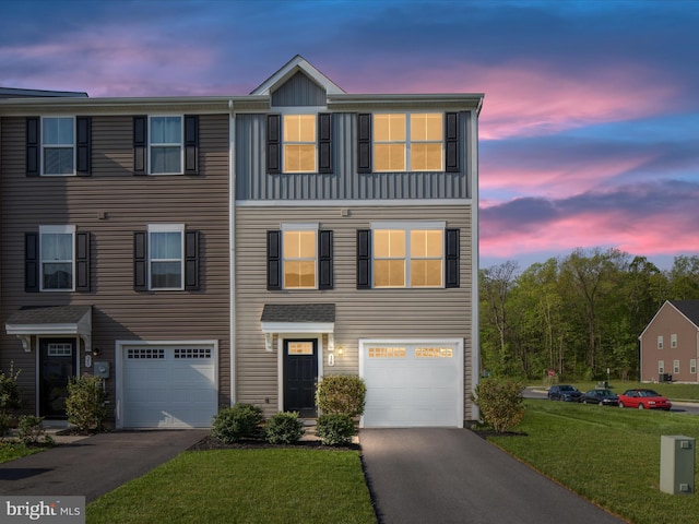 multi unit property featuring an attached garage, driveway, and a front yard