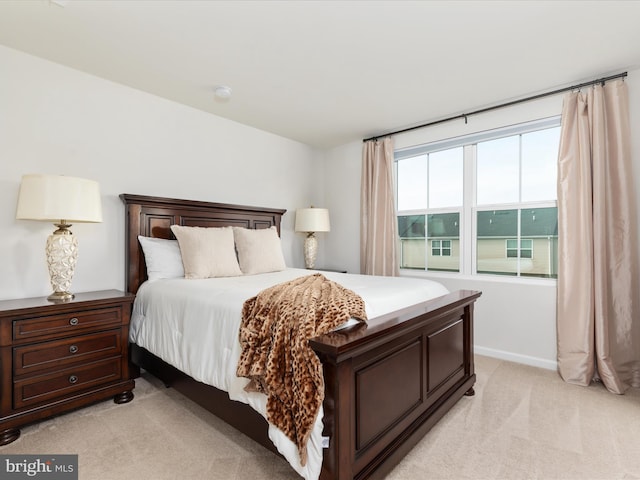bedroom with baseboards and light colored carpet