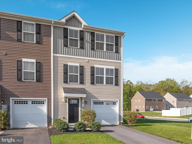 view of property featuring board and batten siding, an attached garage, driveway, and a front lawn