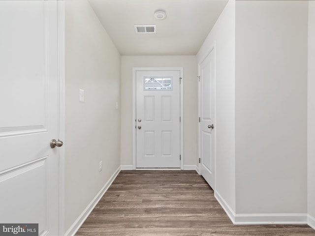 doorway featuring baseboards, visible vents, and wood finished floors