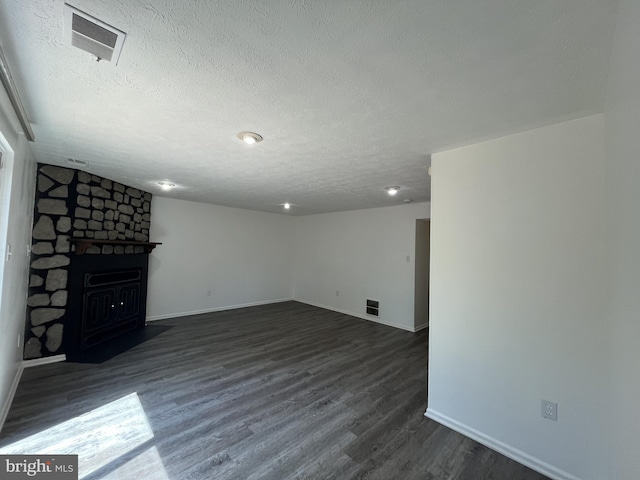 basement featuring a textured ceiling, visible vents, a stone fireplace, and baseboards