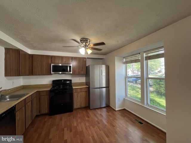 kitchen featuring a textured ceiling, visible vents, a sink, and black appliances